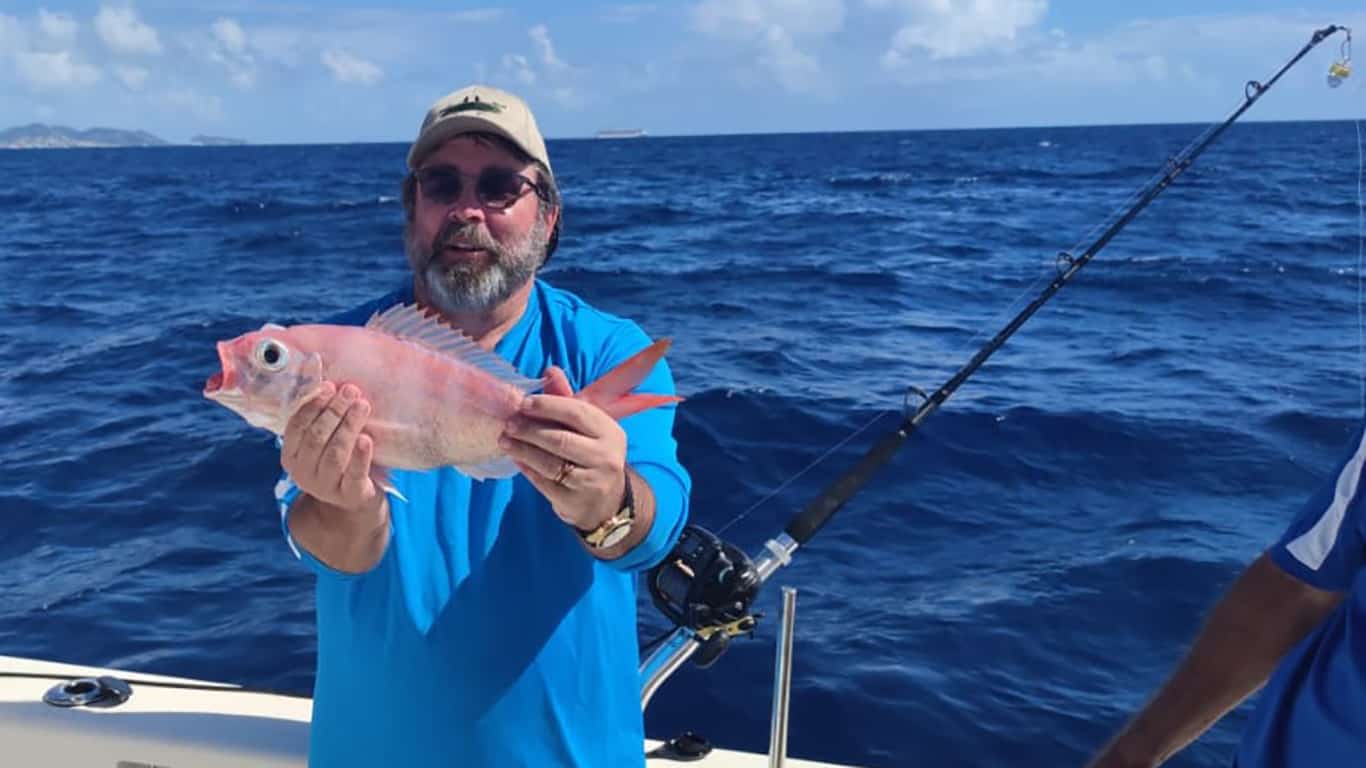A fisherman holds up a Red Snapper